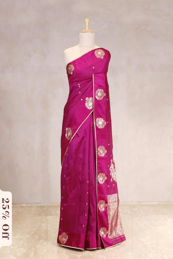 Pink saree with floral patterns on a mannequin against a plain background