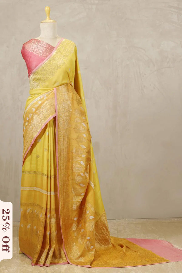 Yellow saree with pink blouse on a mannequin against a plain background