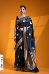Woman wearing a black saree with white patterns on an orange background