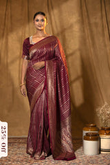 Woman wearing a maroon saree with a gold border against a brown curtain background.