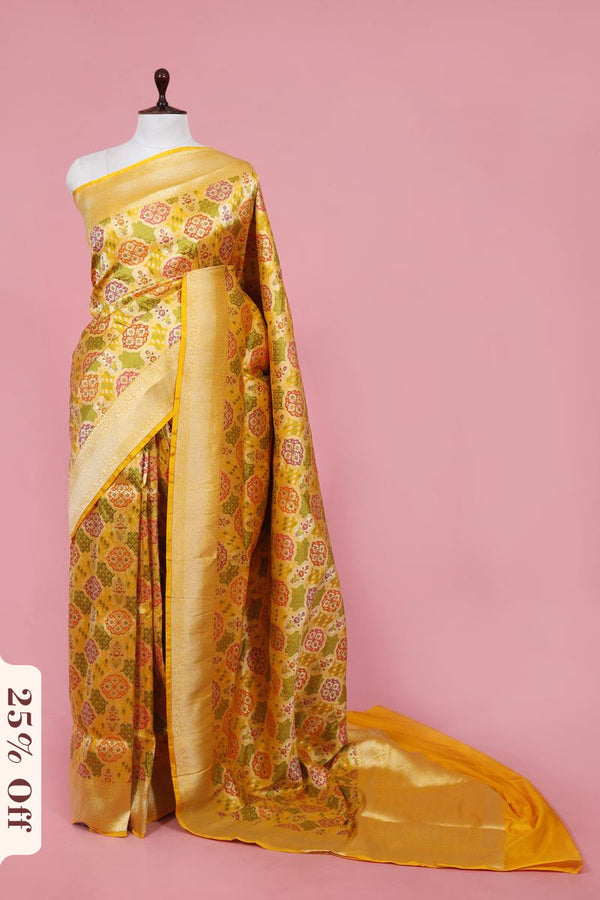 Yellow saree with floral patterns on a mannequin against a pink background