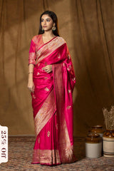 Woman wearing a pink saree with gold patterns against a brown curtain background