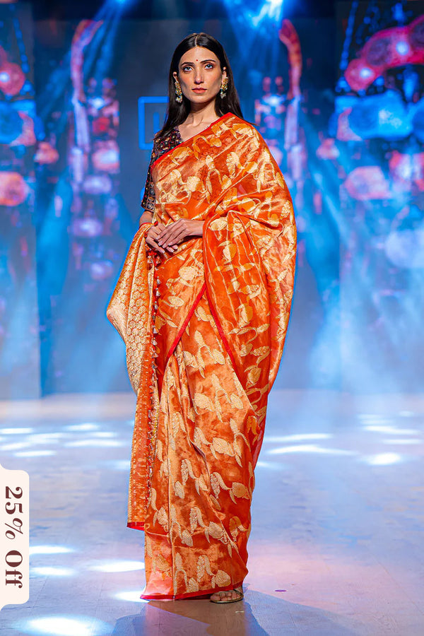 Woman in an orange saree with a pattern on a stage with blue lighting