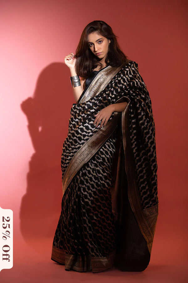 Woman wearing a black and gold saree against a red background