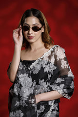 Woman wearing a black floral dress with sheer sleeves against a red background