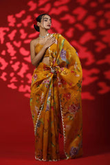 Woman in a yellow floral saree against a red background