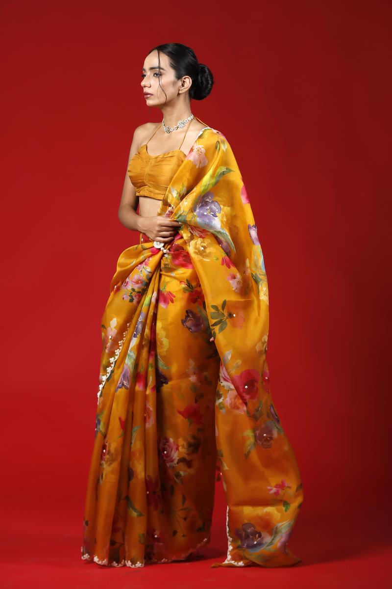 Woman wearing a yellow saree with floral patterns on a red background