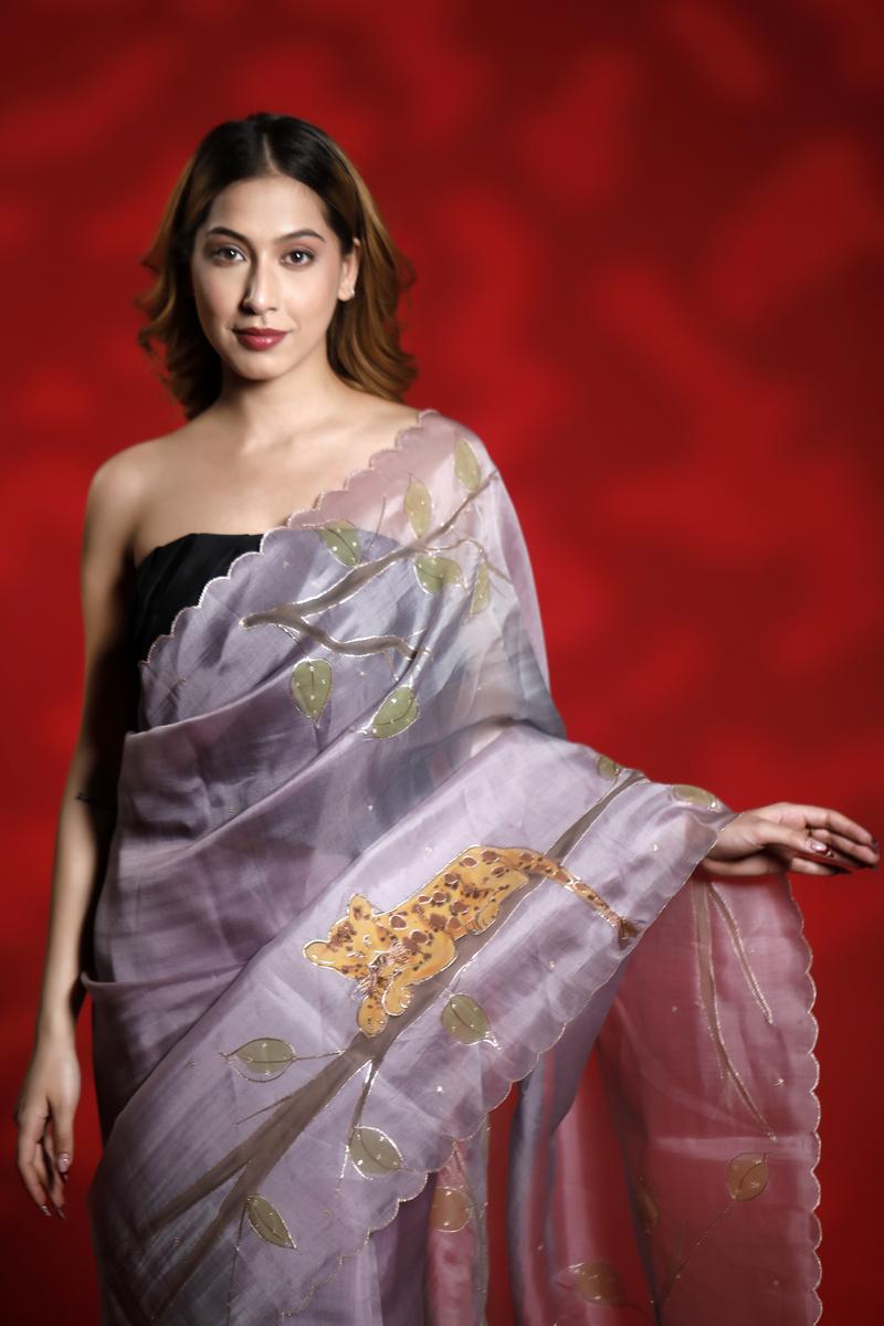 A woman wearing a lilac purple party  wear saree with floral shikargah patterns on a red background