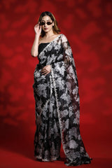 Woman wearing a floral party wear saree dress for a cocktail party looks against a red background
