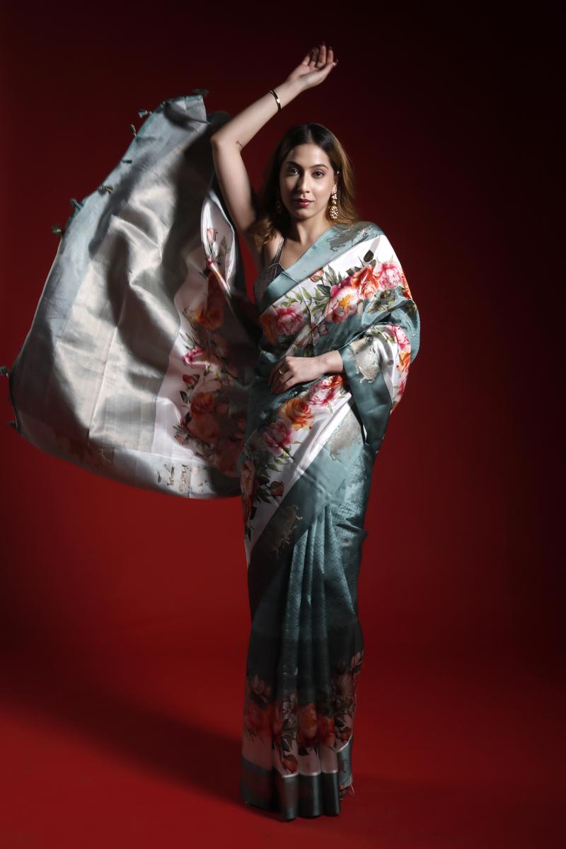 A woman wearing a floral printed Banarasi saree giving a perfect party look against a red background