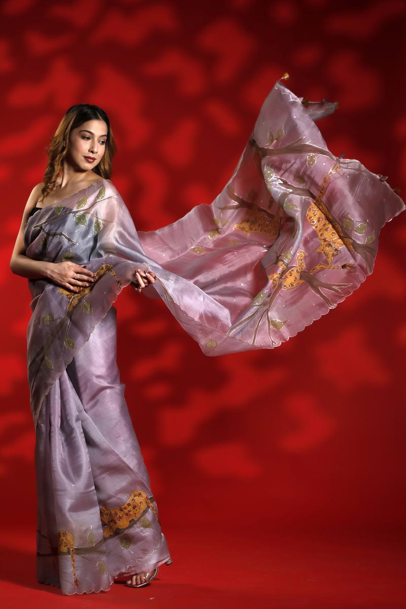 A woman wearing a lilac purple party  wear saree with floral shikargah patterns on a red background
