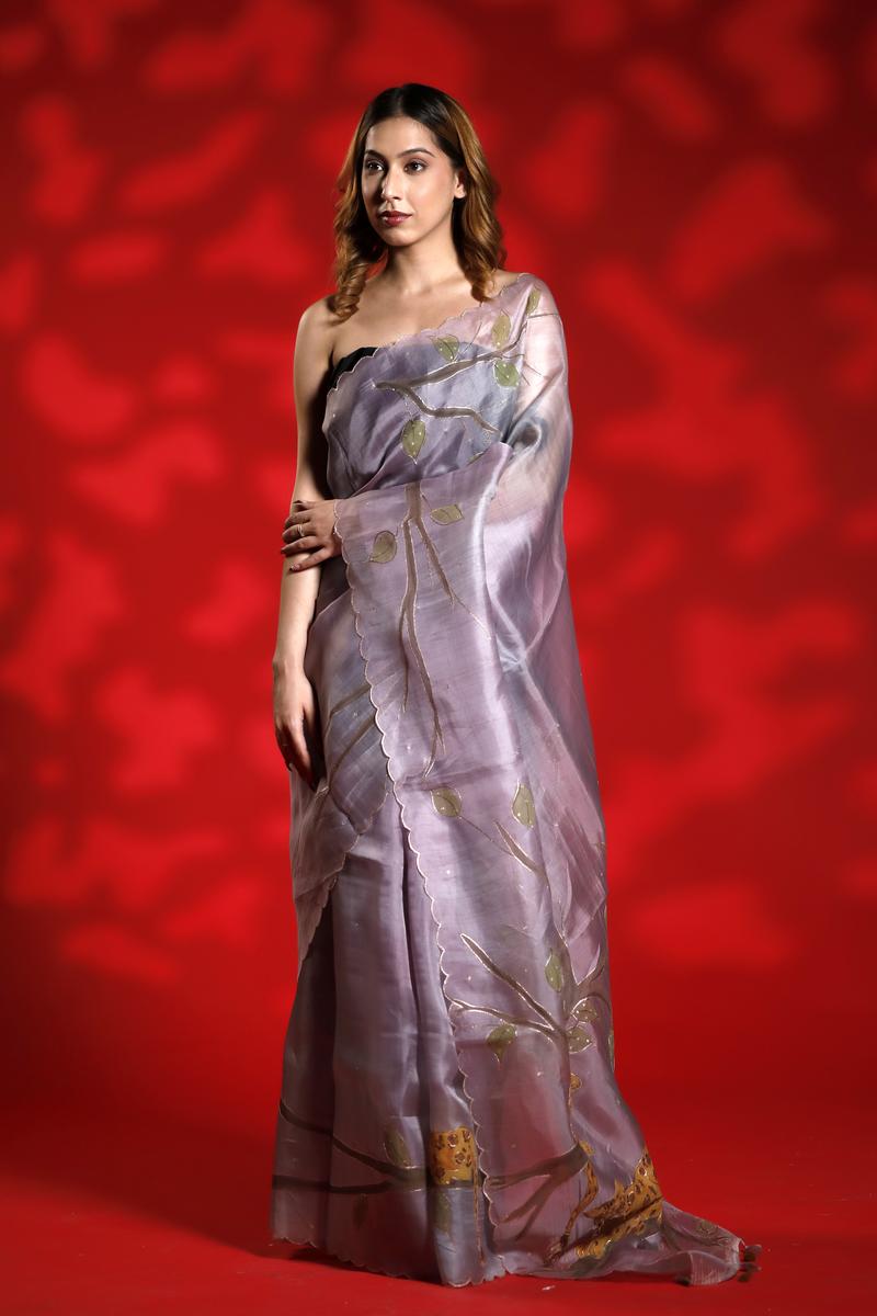 A woman wearing a lilac purple party  wear saree with floral shikargah patterns on a red background