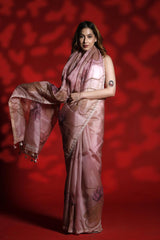 A woman wearing a mauve pink party wear saree with floral pichwai prints against a red background