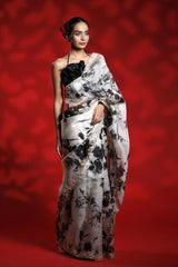 Woman wearing a floral party wear white saree dress for a cocktail party looks against a red background
