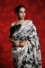 Woman wearing a floral party wear white saree dress for a cocktail party looks against a red background