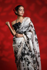 Woman wearing a floral party wear white saree dress for a cocktail party looks against a red background