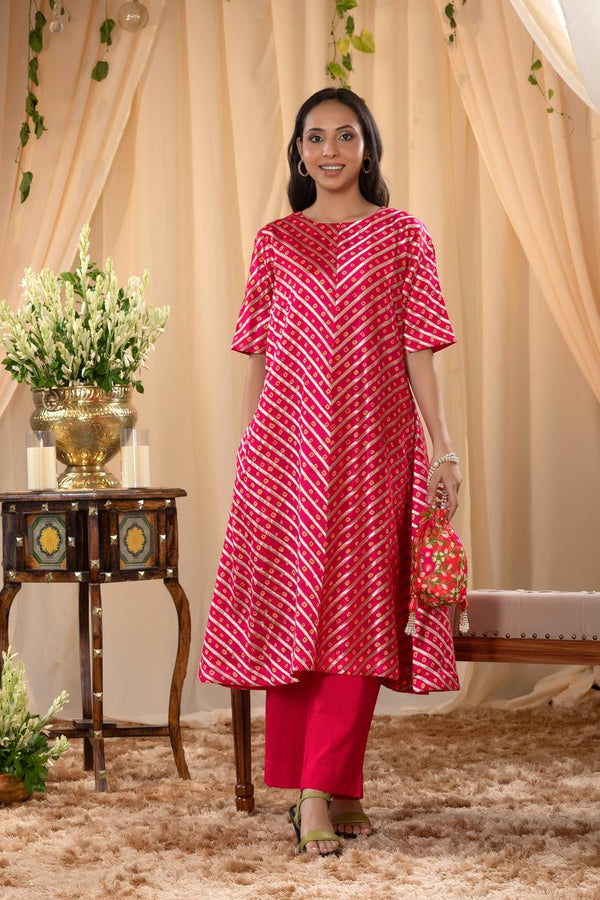 A woman in a pink traditional kurti co-ord set, standing in a decorated indoor setting.