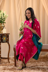 A woman in a traditional pink kaftan co-ord set, sitting on a decorated indoor area.