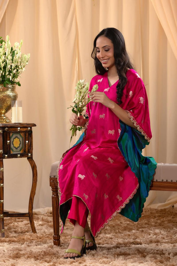 A woman in a traditional pink kaftan co-ord set, sitting on a decorated indoor area.