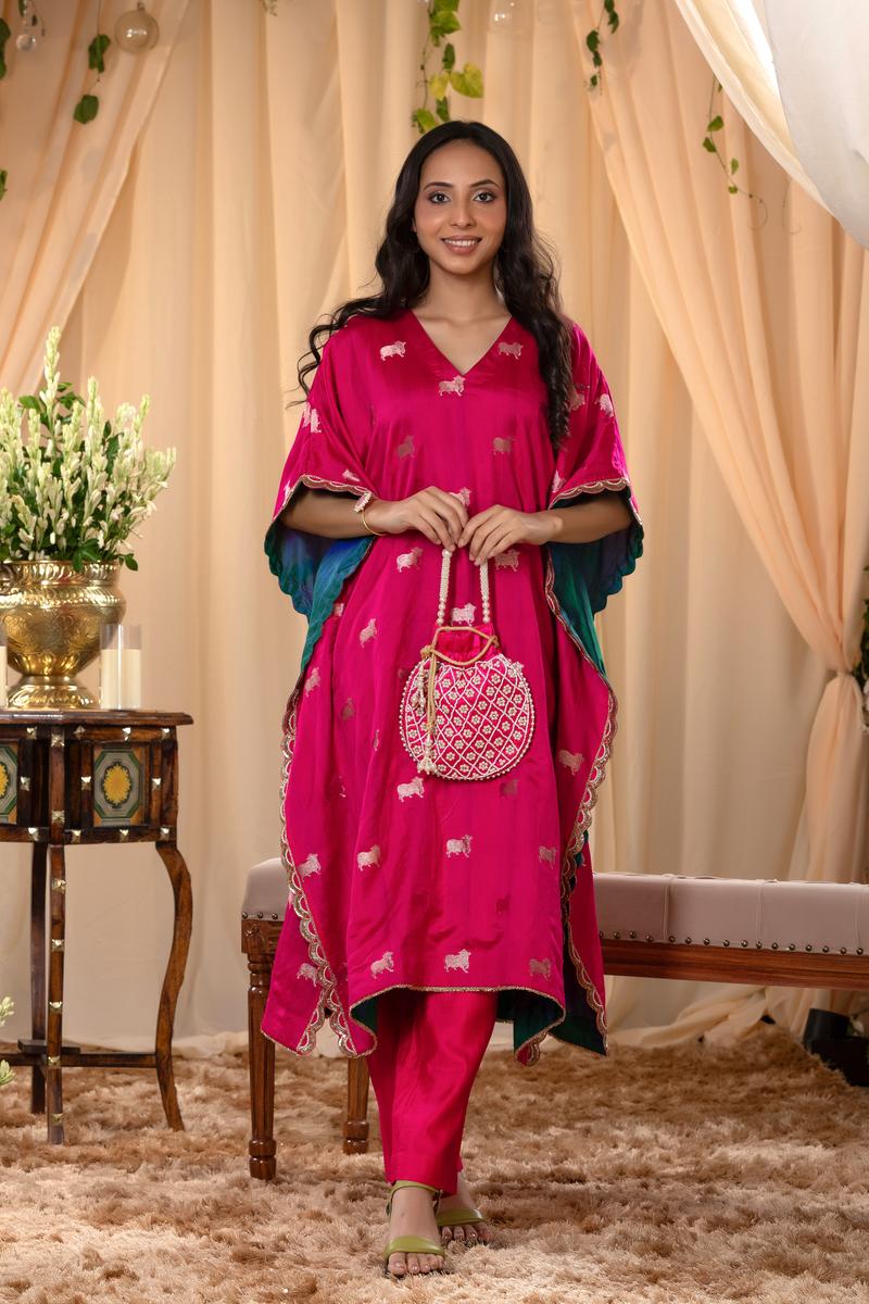 A woman in a pink traditional kaftan co-ord set, standing in a decorated indoor setting.