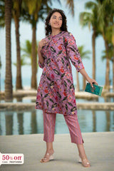 Woman in a floral dress standing by a pool with palm trees in the background