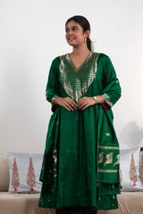 Woman wearing a green traditional outfit with intricate patterns on a white background