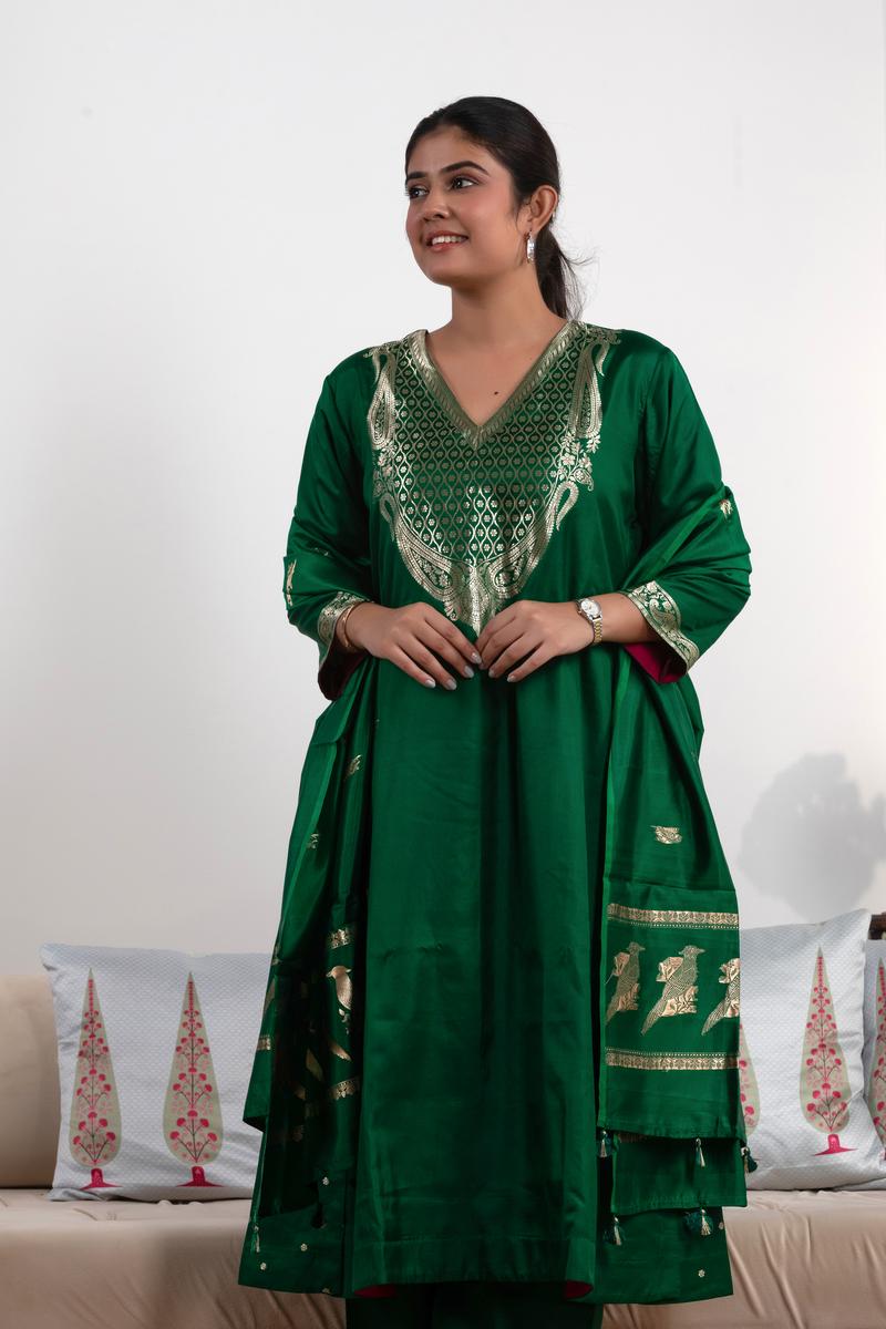 Woman wearing a green traditional outfit with intricate patterns on a white background