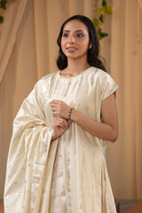A woman in a traditional off white salwar suit and off white banarasi dupatta 