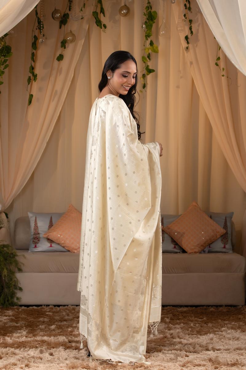 A woman in a traditional off white salwar suit and off white banarasi dupatta 
