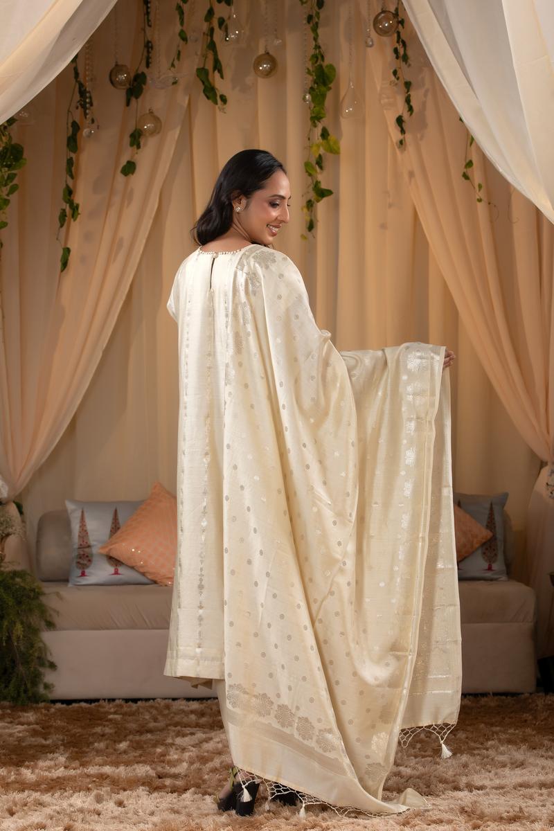 A woman in a traditional off white salwar suit and off white banarasi dupatta 
