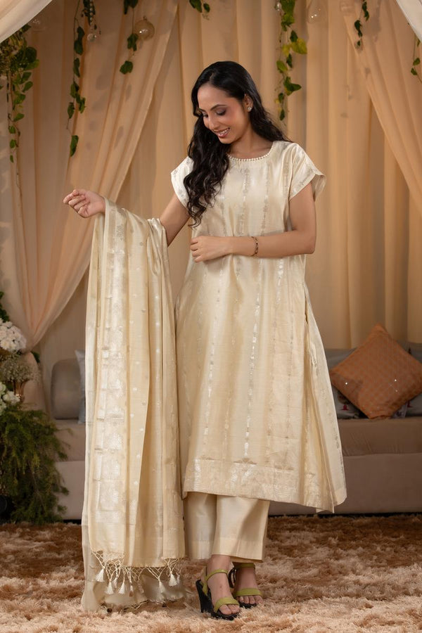 A woman in a traditional off white salwar suit and off white banarasi dupatta 