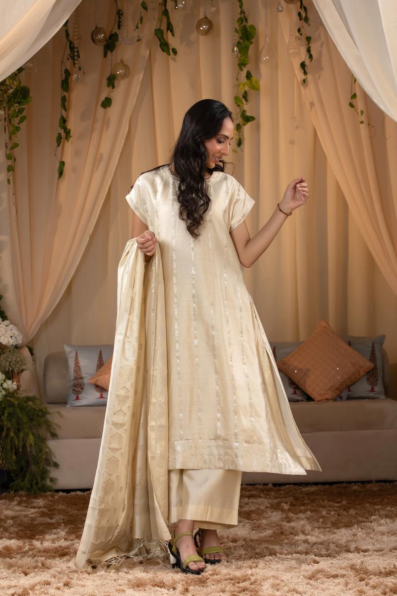 A woman in a traditional off white salwar suit and off white banarasi dupatta 
