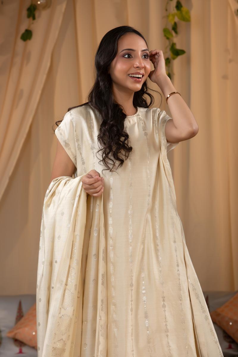 A woman in a traditional off white salwar suit and off white banarasi dupatta 
