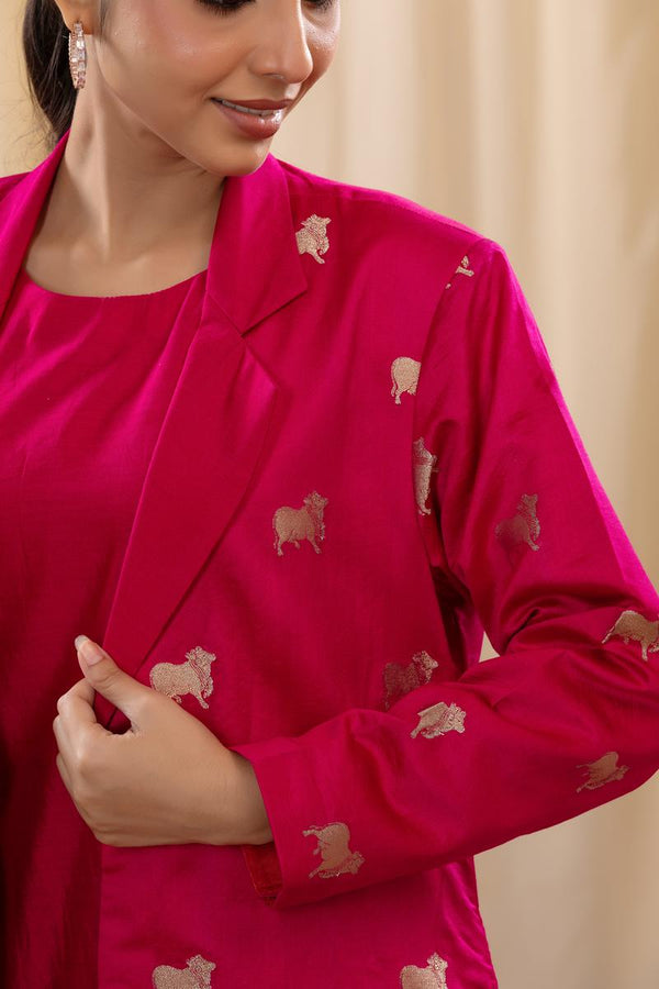 A woman in a pink Indo-Western dress, paired with a matching coat featuring pichwai motifs, in a close view.