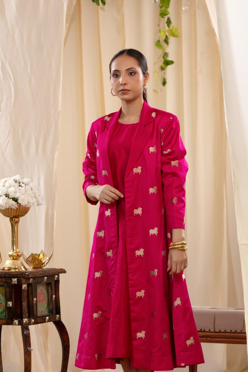 A woman in a pink Indo-Western dress, paired with a matching coat featuring pichwai motifs.