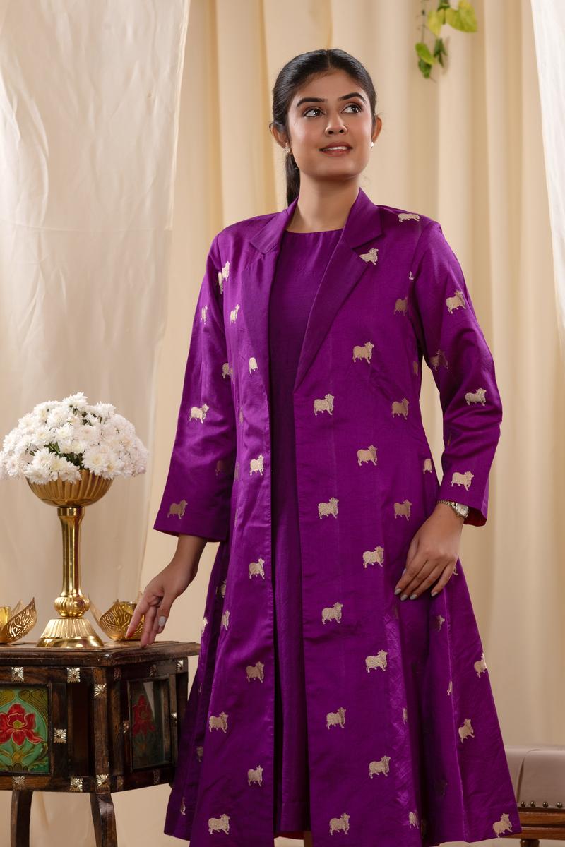 A woman in a purple Indo-Western dress, paired with a matching coat featuring pichwai motifs.