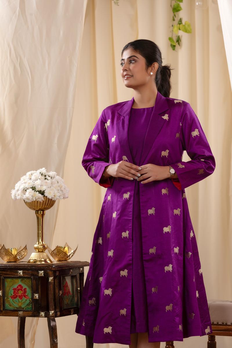A woman in a purple Indo-Western dress, paired with a matching coat featuring pichwai motifs.