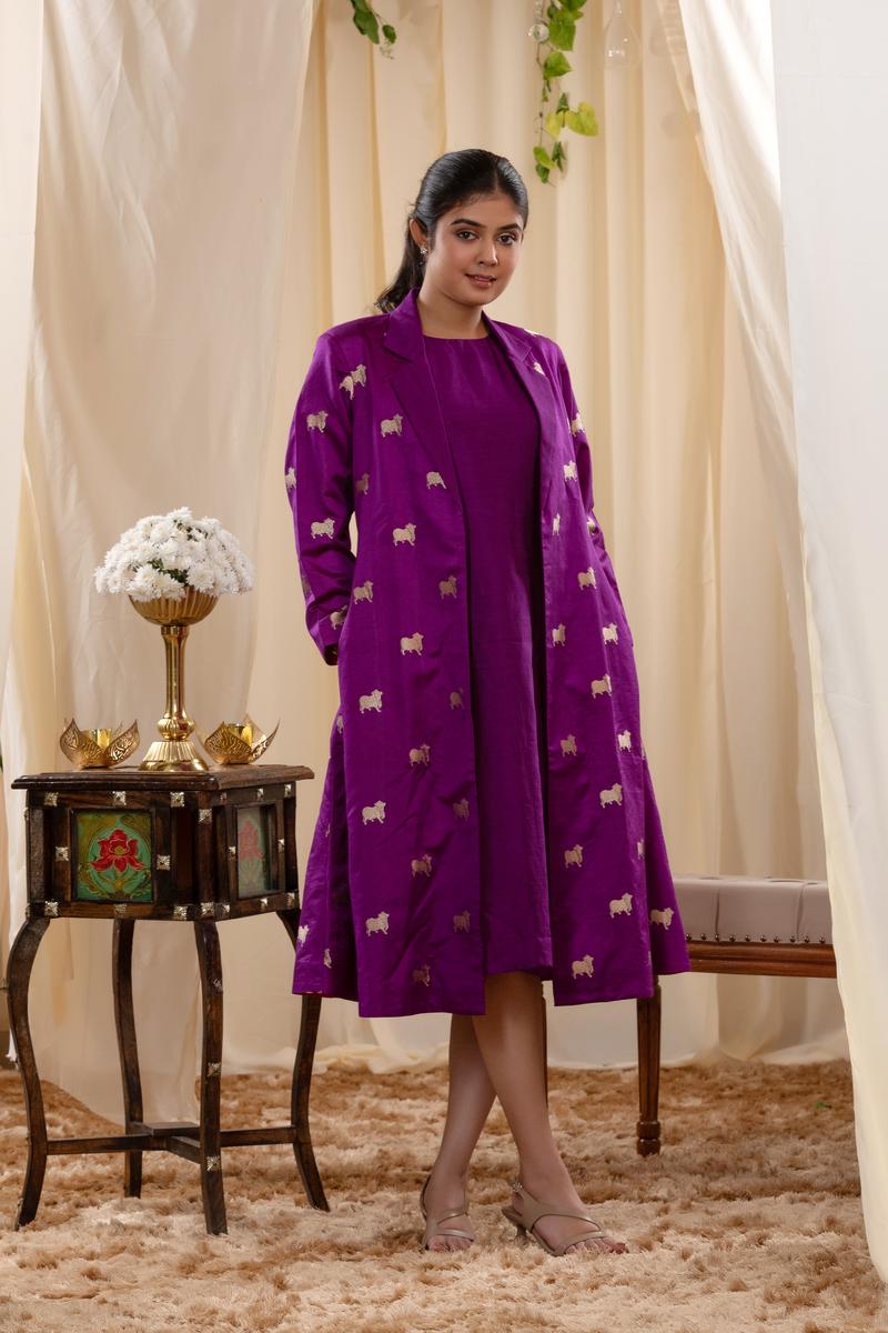 A woman in a purple Indo-Western dress, paired with a matching coat featuring pichwai motifs.