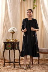 A woman in a black Indo-Western dress, paired with a matching coat featuring pichwai motifs.