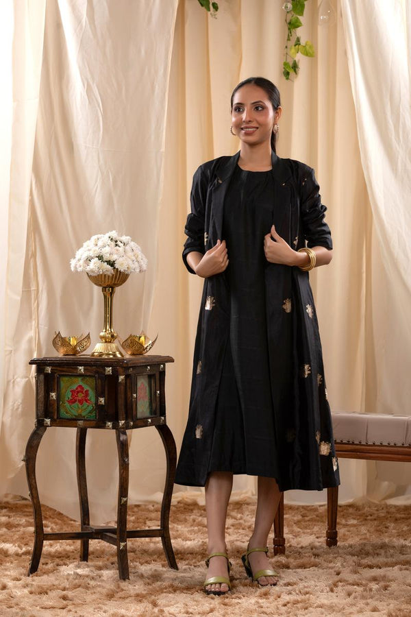 A woman in a black Indo-Western dress, paired with a matching coat featuring pichwai motifs.