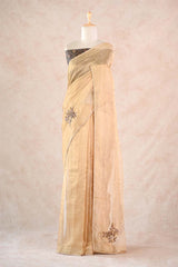 Beige saree with silver embroidery on a mannequin against a light pink background