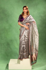 Women Wearing Grey Tissue Silk Saree, party wear saree, gold and silver zari buti and rust brocade pallu with scalloped lace border.