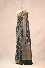 Black floral saree with a gold border on a mannequin against a beige background