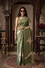 Woman in a green tussar applique saree standing in an ornate room with decorative elements.