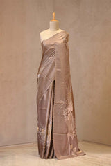 Close up of Grey Tussar Silk Saree showing plain body, floral applique and pitta zari work on the pallu with a scalloped border.