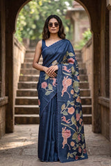 Woman wearing a blue tussar appilque saree with floral shikargha patterns in an outdoor setting