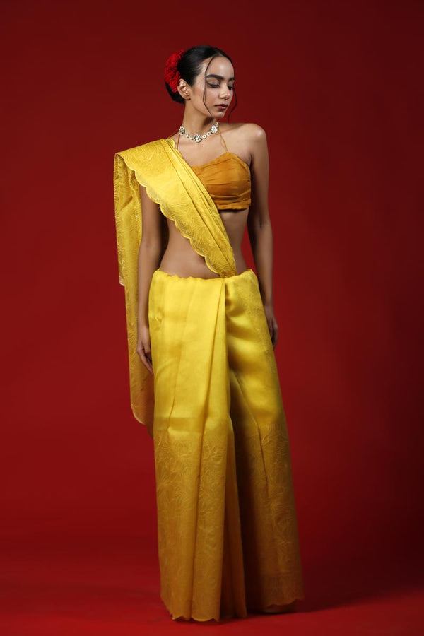 A woman wearing a yellow saree against a red background, promoting Party wear saree